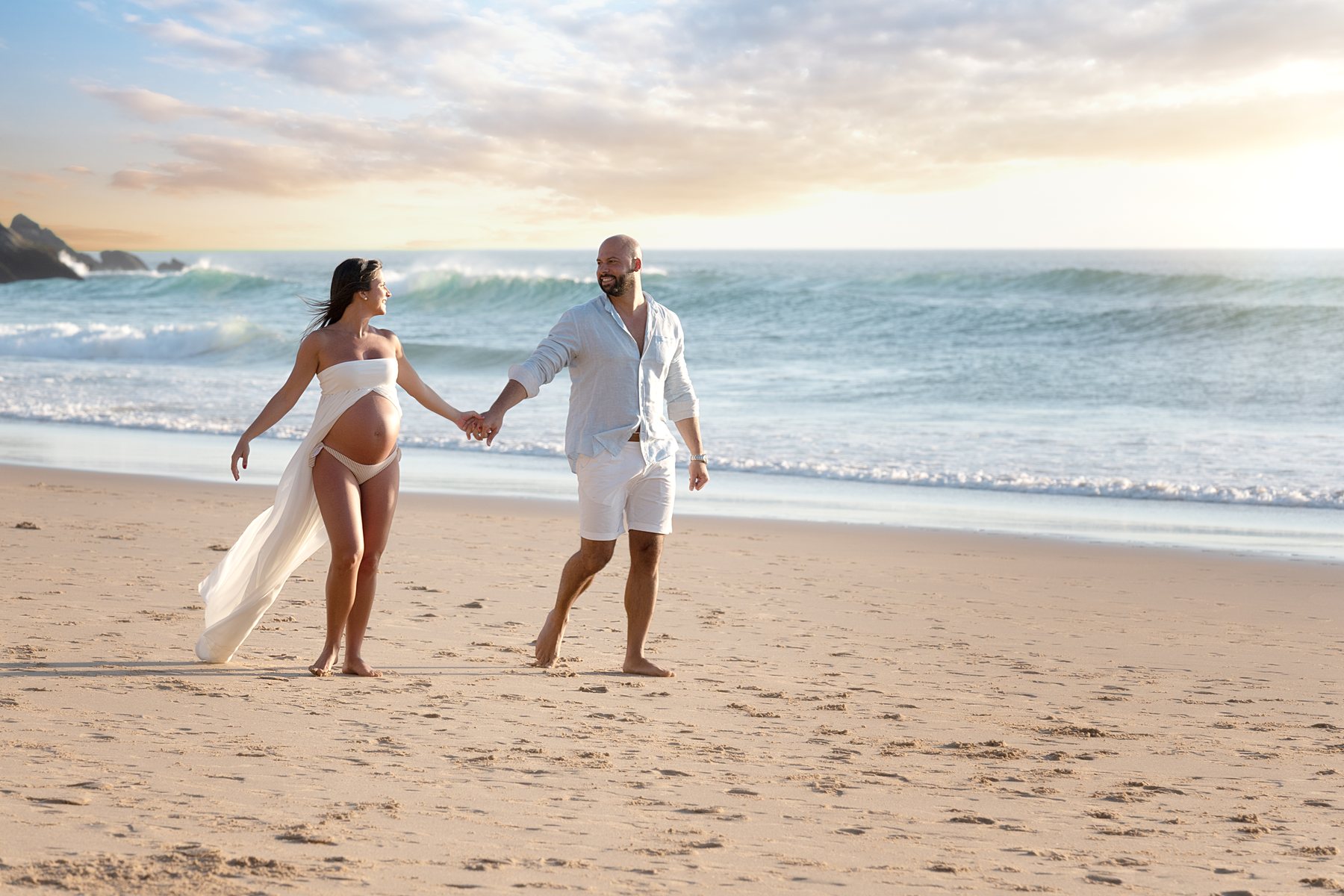 Casal de mãos dadas na praia ao pôr do sol