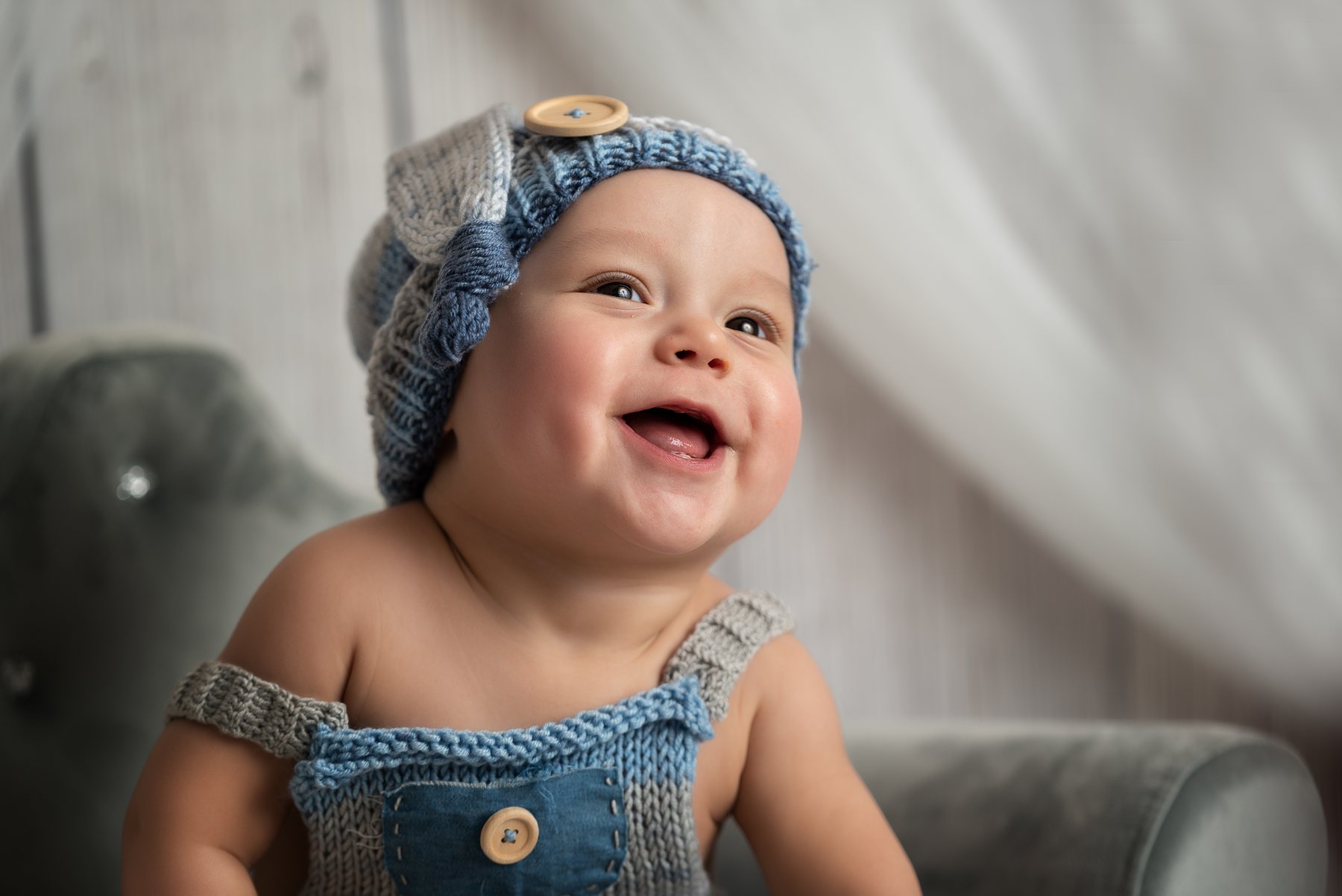 Bebé a rir, de gorro e fato de malha azul